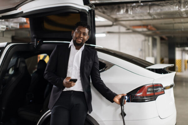 Businessman charging an electric car while smiling