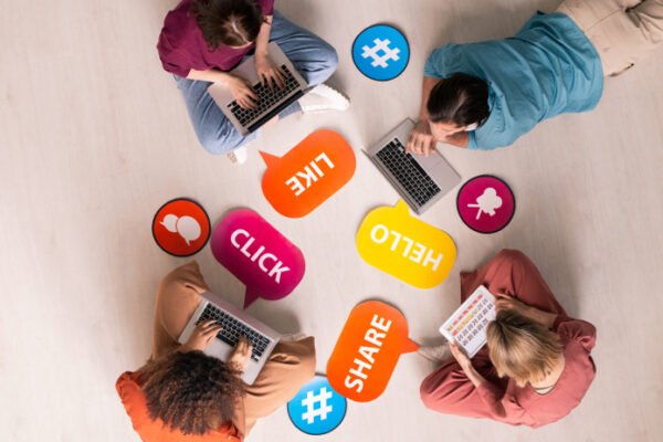 overhead view of 4 people on their computers with superimposed social media icons